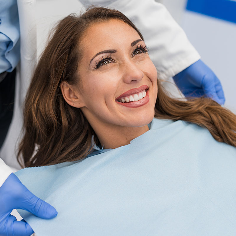 Doctor fixing female patient napkin in modern dental clinic