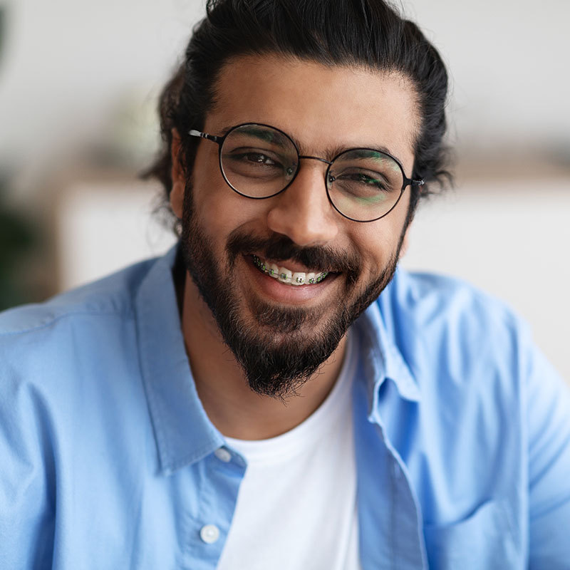 Indian guy with dental braces and eyeglasses smiling