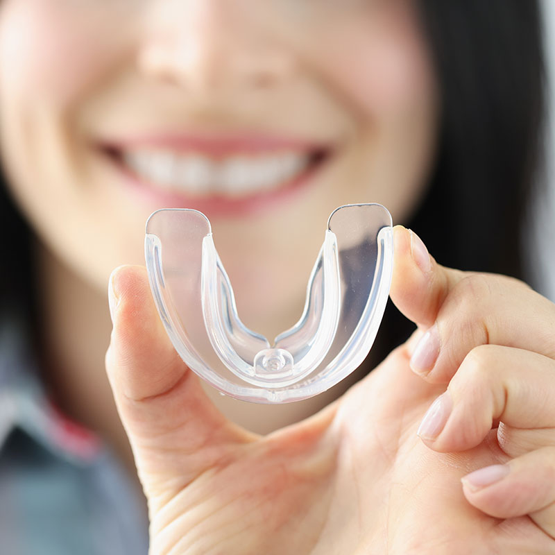 Smiling woman holds transparent plastic mouth guard