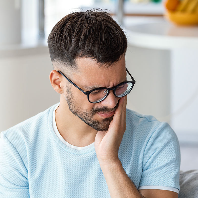 Ill man having toothache and touching cheek