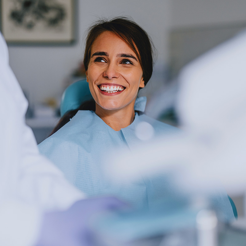 Smiling woman sitting in a dental chair interacting with a dentist during a checkup