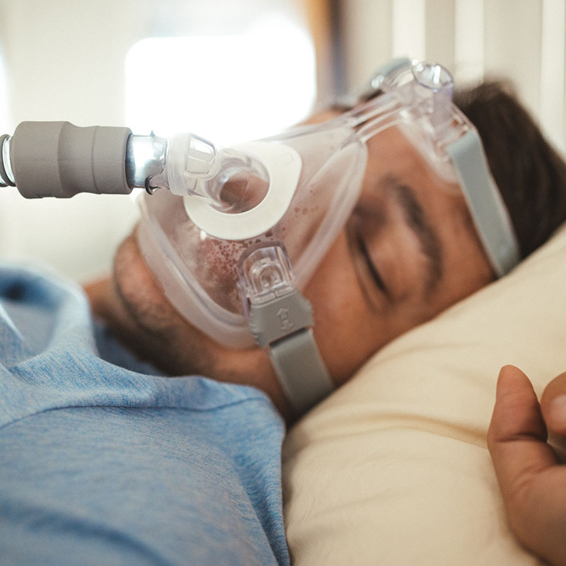 Middle aged man sleeping with Cpap machine mask on for sleep apnea