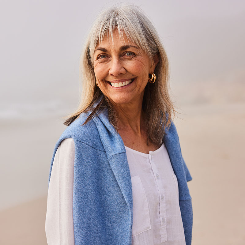 Beautiful woman in her 50s with blue sweater around shoulders, smiling